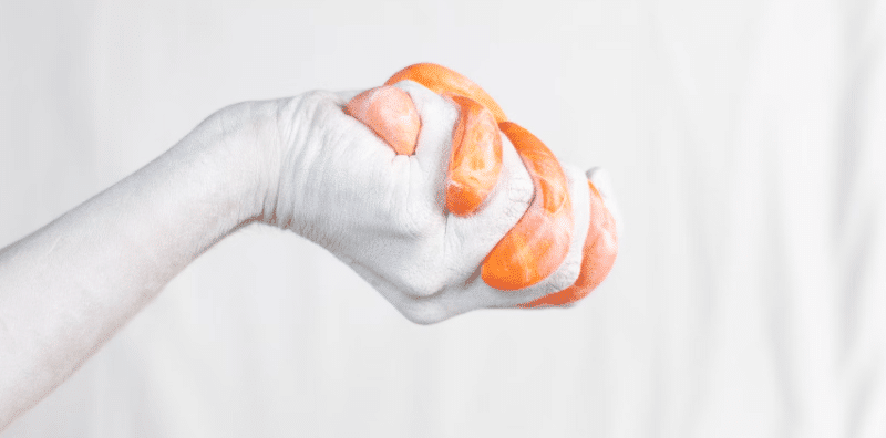 Bijela ruka sa narančastim slime-om u ruci