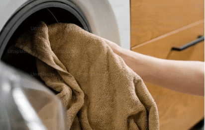 Čovjek ubacuje prljavu odjeću u mašinu za pranje rublja