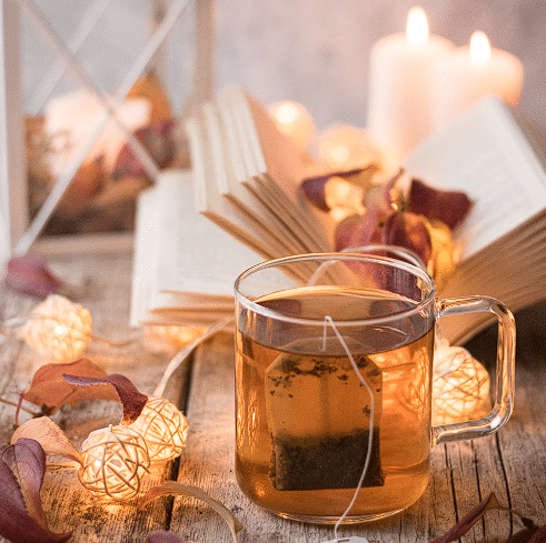 Čaj od đumbira sa knjigom u pozadini i raznim dekoracijama