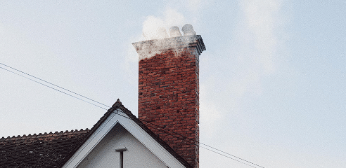 Crveni dimnjak na krovu kroz koji izlazi dim
