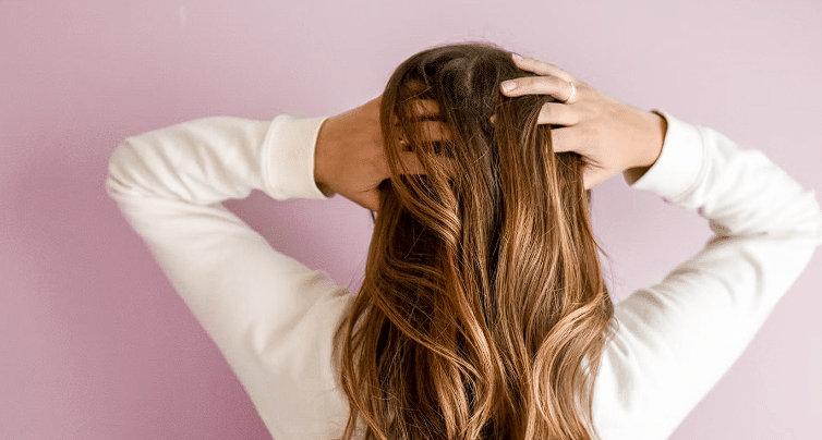 Osoba duge smeđe kose koja provlači ruke kroz kosu
