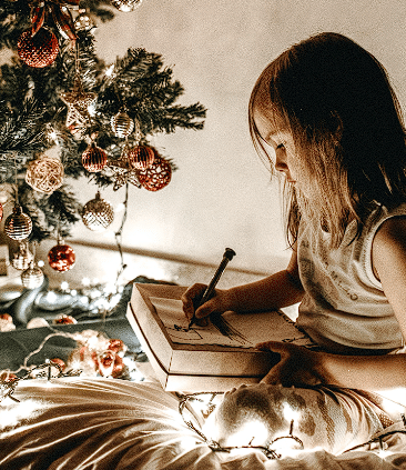 Djevojčica crta olovkom pod božićnom jelkom