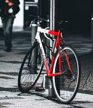 Crveni bicikl naslonjen na stub
