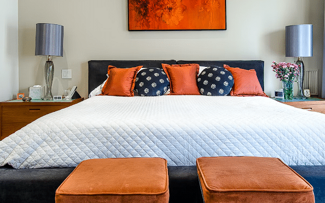 Krevet u sobi sa narančastim jastucima