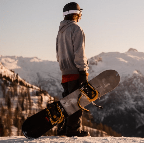 Čovjek koji stoji na planini i drži snowboard